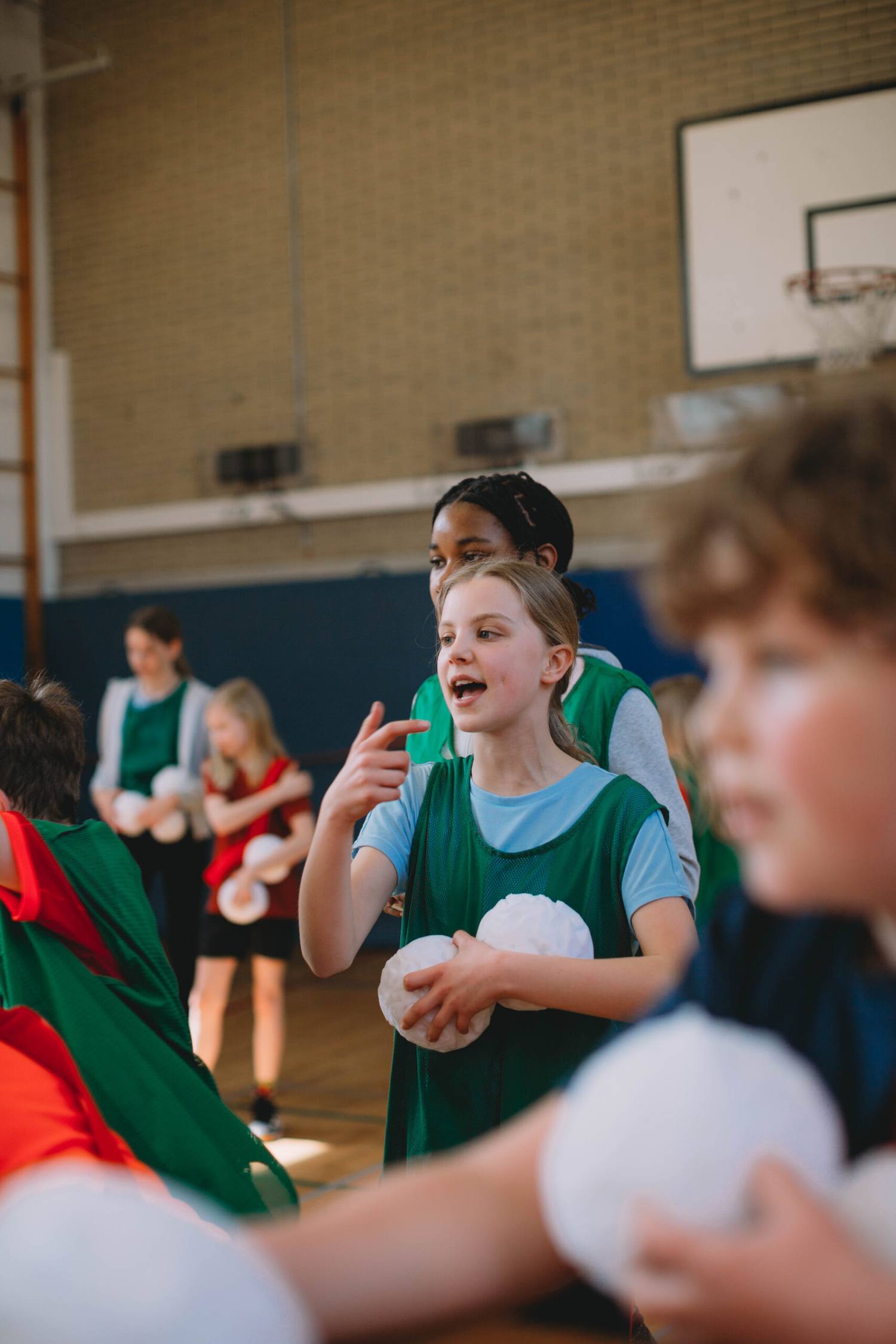 Bambini con casacche verdi giocano con le palle in una società sportiva
